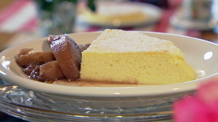 Ein heller Kuchen auf einem weißen Teller garniert mit Pflaumenmus.
