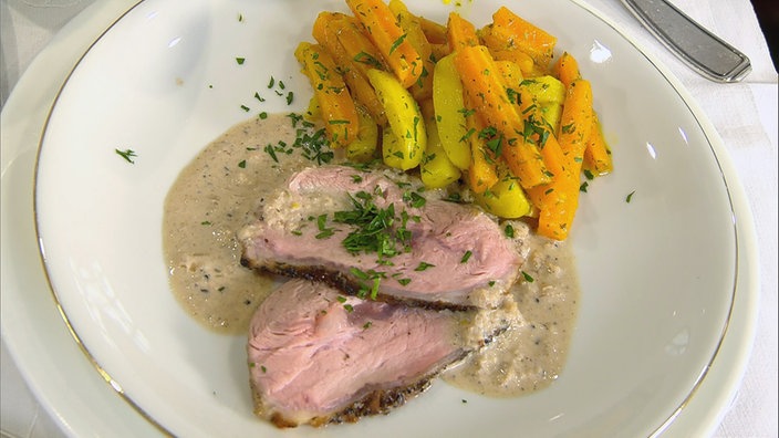 Zwei Scheiben Kalbsschmorbraten mit Möhrengemüse auf einem Teller angerichtet