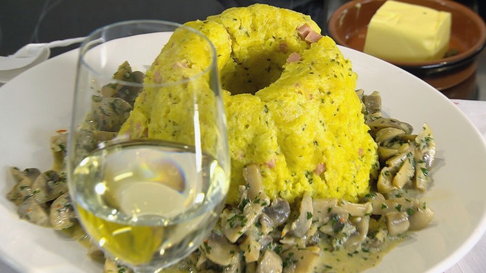 Gestürzter Kartoffelpudding aus Guglhupfform, davor ein Glas Weißwein