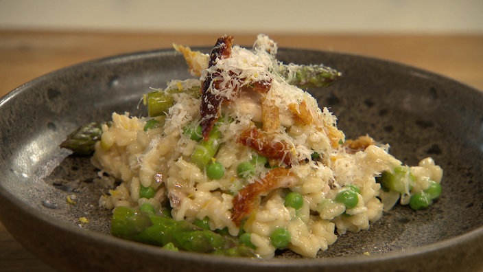 Das Bild zeigt Hähnchen Risotto mit grünem Spargel und Erbsen.