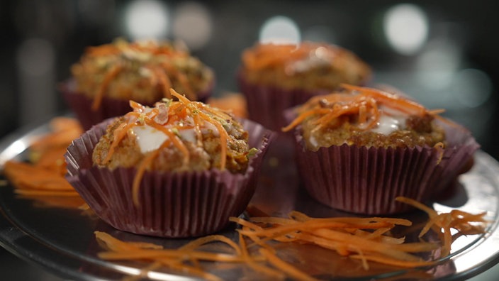 Muffins auf einem Silbertablet mit Möhren-Raspeln obendrauf.