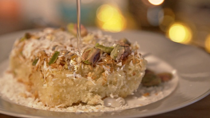 Syrischer Grießkuchen mit Pistazien dekoriert wird mit Sirup beträufelt