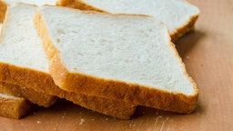 Mehrere Scheiben Toastbrot liegen aufgeschnitten auf einem Tisch.
