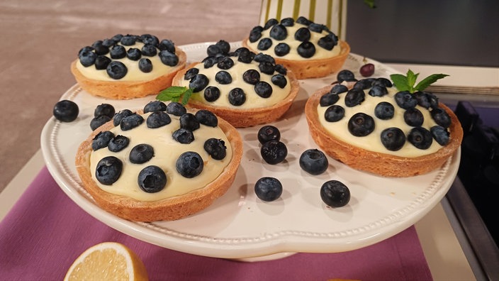 Blaubeer-Tartelettes serviert mit frischen Blaubeeren.