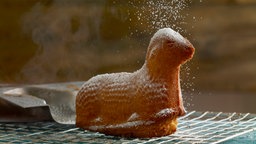 Osterlamm auf Abkühlgitter wird mit Puderzucker bestreut.