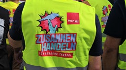 Warnweste mit der Aufschrift "Zusammen handeln. Für bessere Tarife!"