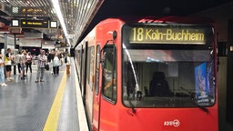 Rechts die SBahn der Linie 18, die am Bonner Hbf hält. Links Menschen warten Menschen am Gleis.