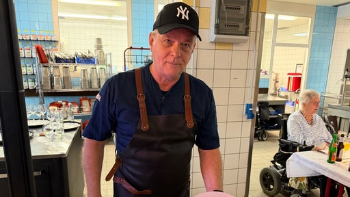Ein Koch steht in der Küche mit einem Teller mit Lachs