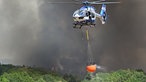 Helikopter der Polizei mit Wasser in einem Löschwasser-Außenlastbehälter beim Waldbrand im Hürtgenwald