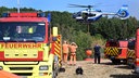 Ein Helikopter der Bundespolizei nimmt Wasser neben Feuerwehrfahrzeugen auf beim Brand im Hürtgenwald