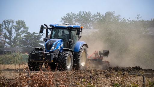 Ein Traktor zieht auf einem Feld mit einem Pflug eine Schneise gegen das Feuer, beim Kampf gegen den Waldbrand im Hürtgenwald