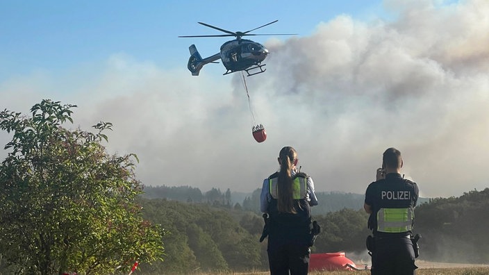  Ein Polizeihubschrauber mit Löschwasser-Außenlastbehälter startet zum Einsatz bei den Löscharbeiten beim Waldbrand im Hürtgenwald