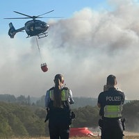  Ein Polizeihubschrauber mit Löschwasser-Außenlastbehälter startet zum Einsatz bei den Löscharbeiten beim Waldbrand im Hürtgenwald