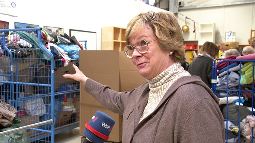Eine Frau zeigt auf Kleiderspenden
