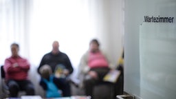 Mehrere Personen sitzen in einem Wartezimmer