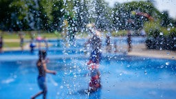 Wasserspeier sprühen Wassertropfen auf einen Wasserspielplatz im Kölner Grüngürtel.