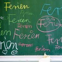 Schüler schreibt "Ferien" an eine Tafel