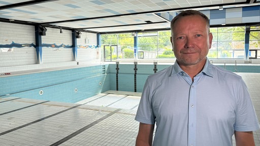 Andreas Sauerwein steht in einem leeren Hallenbad.