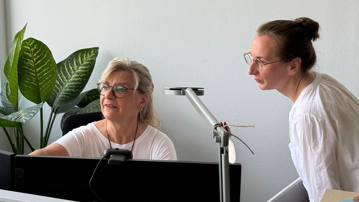 Zwei Frauen unterhalten sich im Büro.