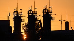 Die Sonne geht hinter technischen Anlagen eines Erdgasspeichers unter
