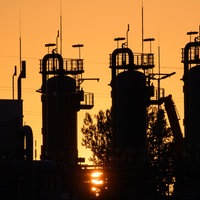 Die Sonne geht hinter technischen Anlagen eines Erdgasspeichers unter