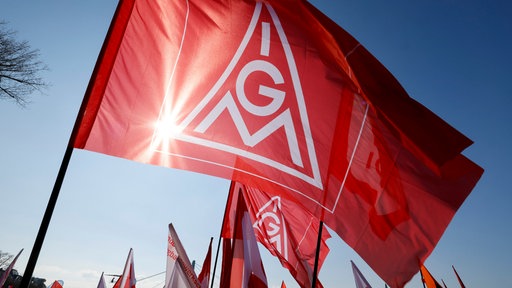 Teilnehmer halten bei einem bundesweiten Aktionstag Flaggen mit dem Logo der IG Metall hoch