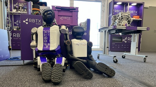 Humanoide Roboter sitzen nebeneinander arbeitslos auf dem Boden