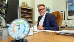 Bernhard Rappenhöner sitzt an Schreibtisch mit Thermometer