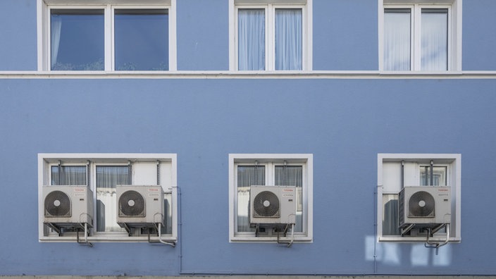 Klimaanlagen vor dem Fenster eines Mietshauses.