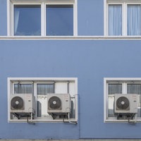 Klimaanlagen vor dem Fenster eines Mietshauses.