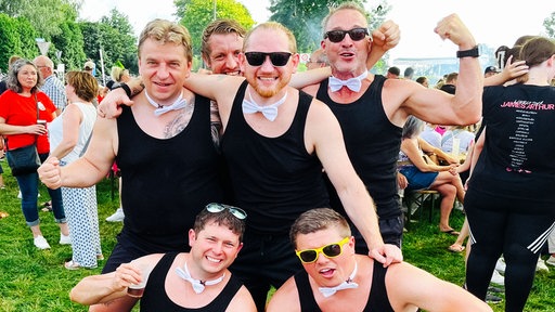Fünf Männer posieren in schwarzem Tanktops und weißen Fliegen um den Hals