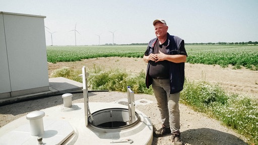 Landwirt Heinz-Gerog Olligs steht neben einem Brunnen.