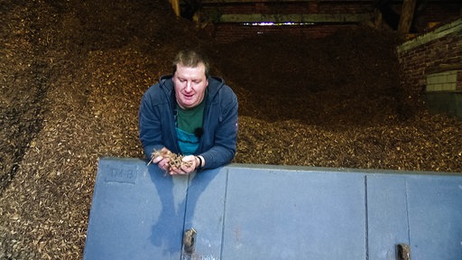 Landwirt Thomas Ostendorf aus Ochtrup steht vor einem riesigen Haufen Hackschnitzel.