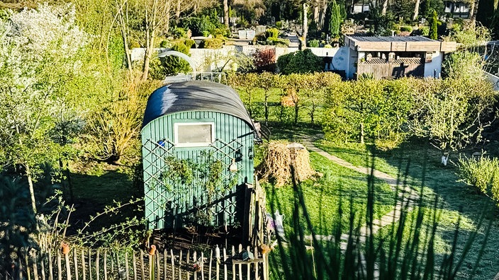 Ein grüner Bauwagen in einem umzäunten Garten