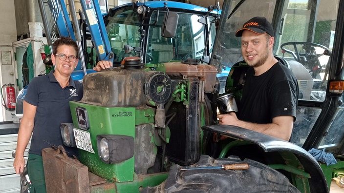 Eine Frau und ein Mann vor einem Traktor