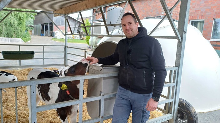 Philipp Terhorst streichelt ein Kalb auf einem Milchhof im Münsterland.