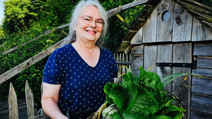 Silvia Albers hält glücklich einen Kiste gefüllt mit Gemüse und Obst, das sie auf der Kleinodfarm geerntet hat. 
