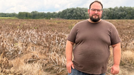 Landwirt Julian Freisendorf steht vor einem seiner Felder und schaut in die Kamera.