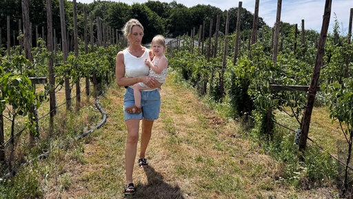 Alina Schmittgen mit Tochter Carla (3) auf einer Plantagen für Obst, das auf dem Hof Maaßen direkt vermarktet wird