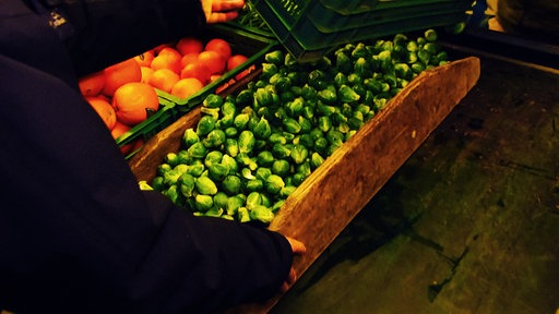 Rosenkohl wird auf einem Markt in die Auslage gefüllt.