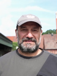 Der Bauer Reinhard Höltmann guckt in die Kamera und im Hintergrund zeigt sich sein Hof.