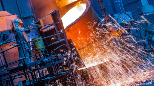 Die Temperatur von flüssigem Eisen wird von Arbeitern in einer Eisengießerei vor der Weiterverarbeitung kontrolliert.