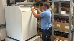 Heizungsbauer Niklas Roßbach installiert ein Heizsystem im Keller eines Hauses. 