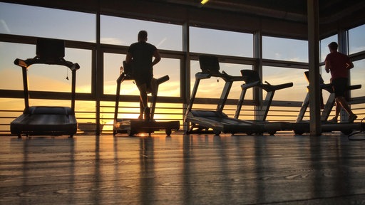 Sportler trainieren im Fitnessstudio bei Sonnenaufgang