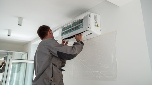 Ein Handwerker installiert eine Klimaanlage in einem Zimmer