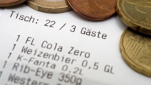Münzen liegen auf einer Restaurantquittung.