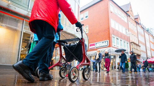 Eine Rentnerin ist mit ihrem Rollator in der Innenstadt unterwegs.