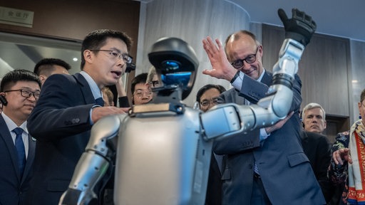 Bundeskanzler Friedrich Merz (CDU) besucht die Firma Unitree Robotics in der Provinz Zhejiang und lässt sich von Gründer und Geschäftsführer Wang Xingxing (l) durch die Präsentationsräume führen.