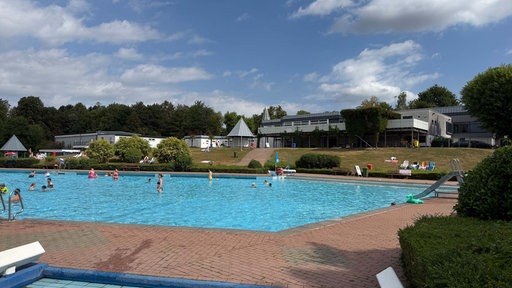 Mehrere Menschen planschen im Freibad.