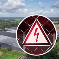 Eine große Solaranlage aus der Luft, auf dem Bild liegt ein Strom-Warnschild.